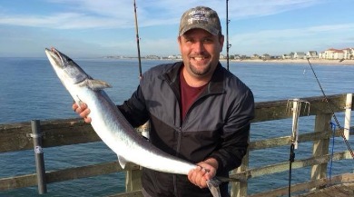 man holding a caught fish on seaview pier | Coastline Realty Vacations
