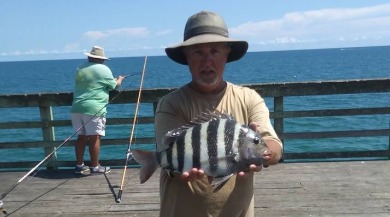 man holding a caught fish on jolly roger pier | Coastline Realty Vacations