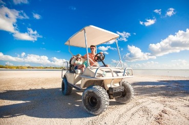 family riding golf cart on the beach | Coastline Realty