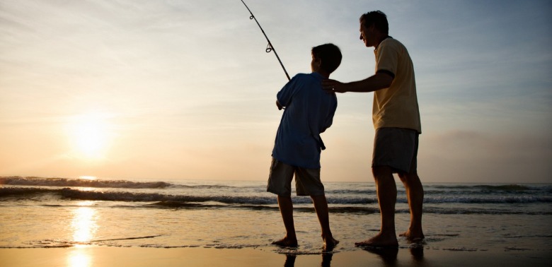 son and father surf fishing | Coastline Realty Vacations