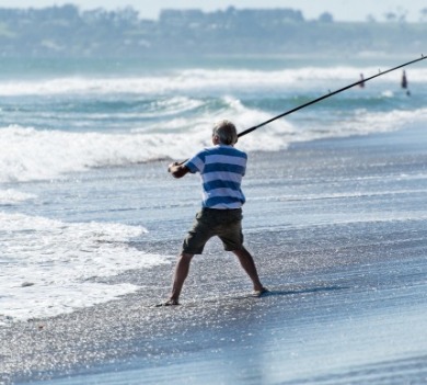 man surf fishing on beach | Coastline Realty Vacations