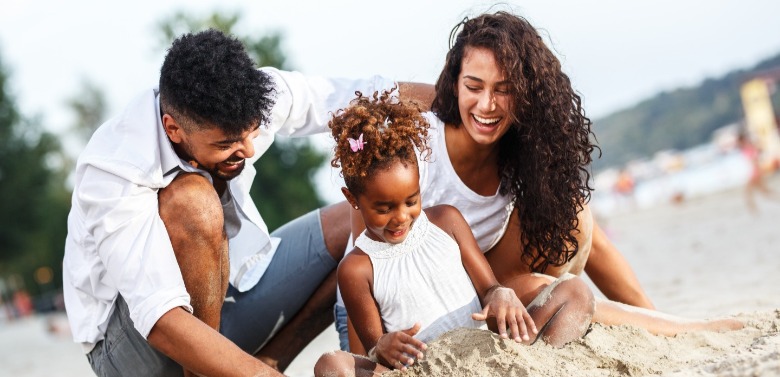 family playing in the sand on the beach | Coastline Realty